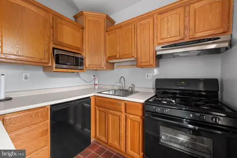 a kitchen with stainless steel appliances granite countertop a stove top oven a sink dishwasher and cabinets with wooden floor