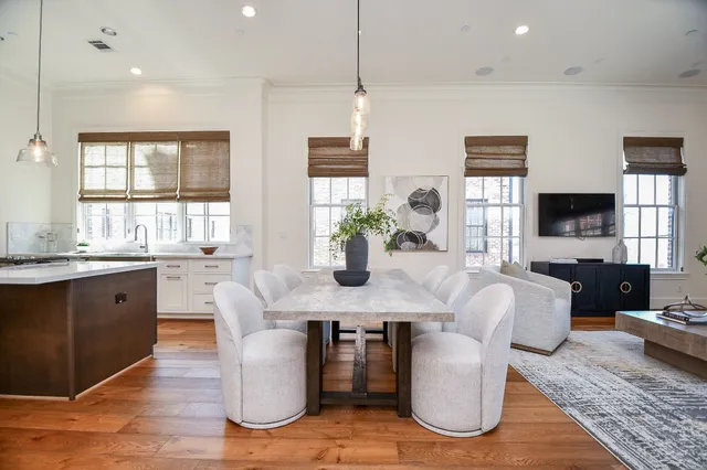 a dining room with furniture a potted plant and a kitchen view