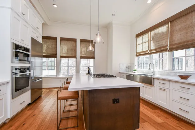 a kitchen with stainless steel appliances kitchen island granite countertop a stove a sink and white cabinets with wooden floor