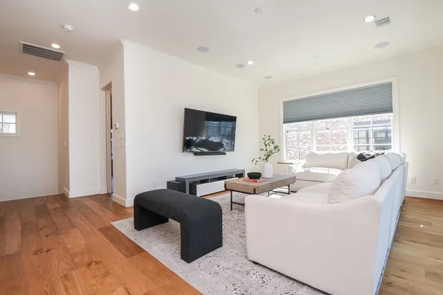 a living room with furniture a flat screen tv and a large window