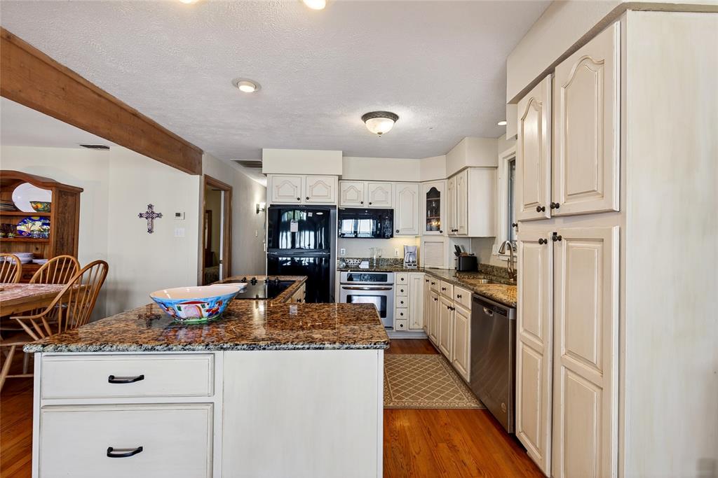 1113 Rim O The World Drive Tool, TX 75143 - Photo 8 of 40 Kitchen featuring a central island with granite countertop, cabinetry, stainless steel appliances and dishwasher, and oak hardwood flooring.