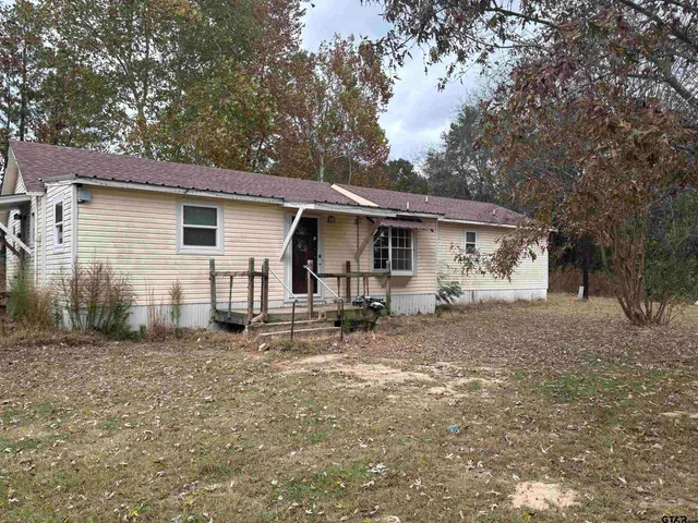 a view of a house with a yard and large tree