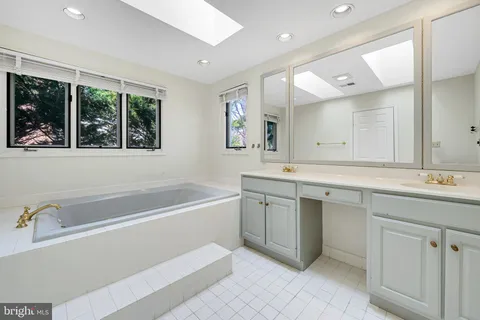 a bathroom with a tub a sink double vanity and a mirror
