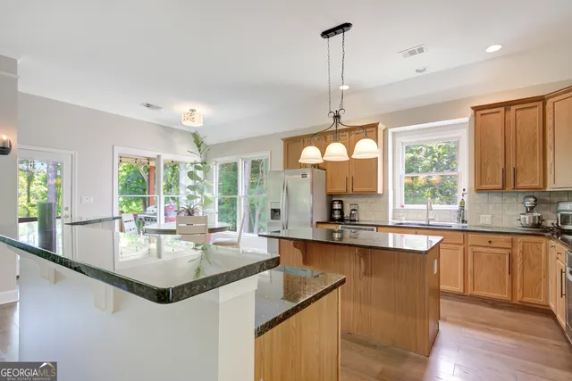 a kitchen with stainless steel appliances granite countertop a sink a stove a refrigerator and island with wooden floor