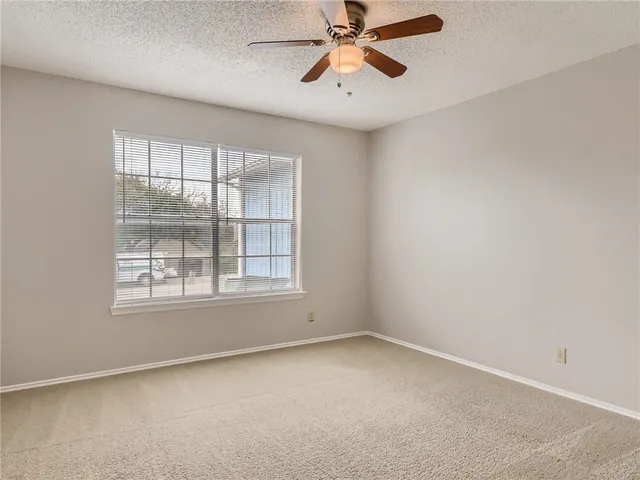 an empty room with a window and a fan