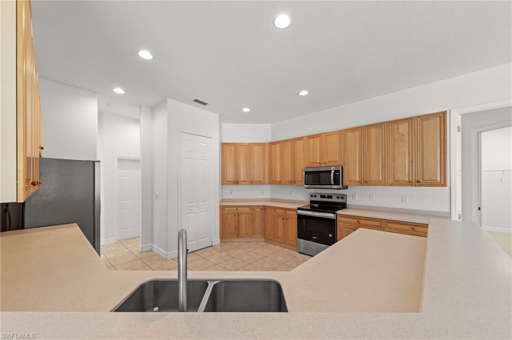 9623 Springlake Circle Estero, FL 33928 - Photo 15 of 47 a kitchen with stainless steel appliances kitchen island granite countertop a sink a stove and cabinets