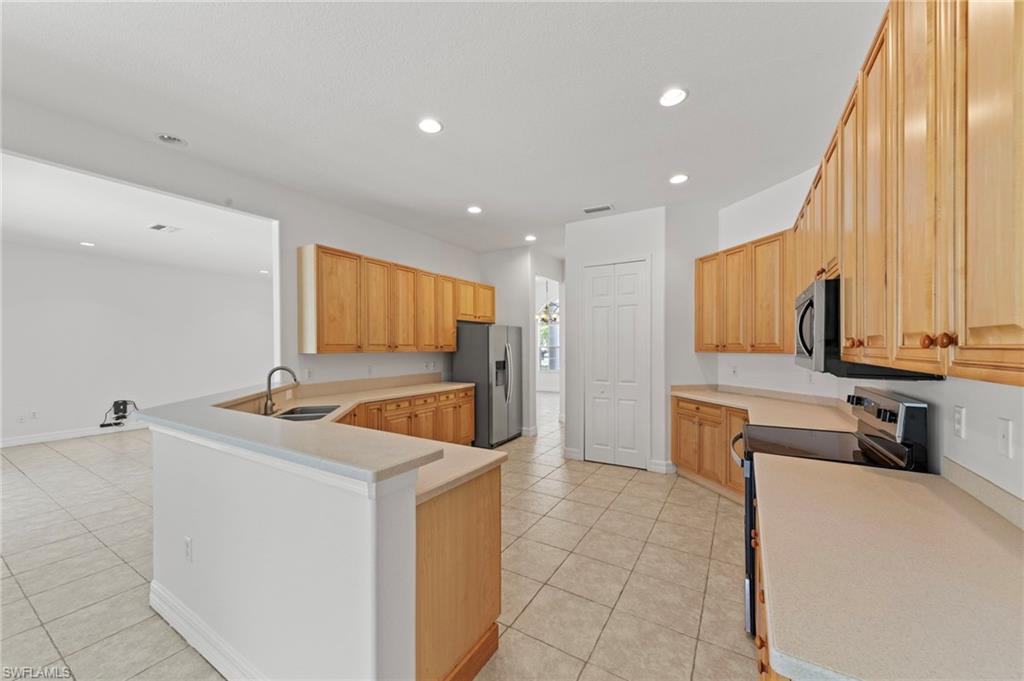 9623 Springlake Circle Estero, FL 33928 - Photo 16 of 47 a kitchen with stainless steel appliances a stove top oven a sink a refrigerator and white cabinets