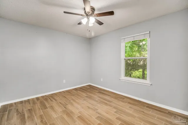 an empty room with a window and a fan