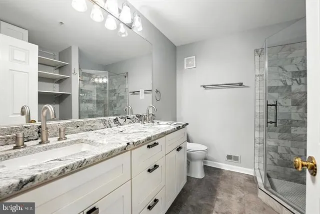 a bathroom with a granite countertop sink a toilet and shower