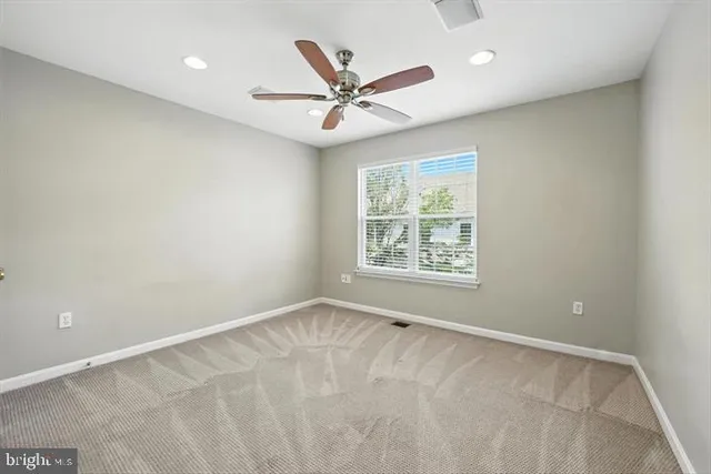 an empty room with window and ceiling fan