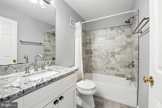 a bathroom with a granite countertop sink a toilet and shower