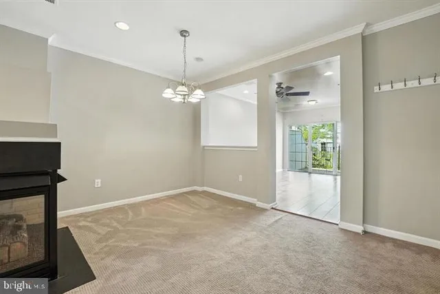 an empty room with chandelier fan and windows