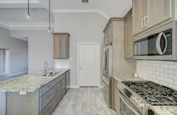 a kitchen with granite countertop a sink stove and refrigerator
