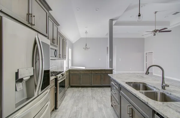a kitchen with granite countertop a sink stove and refrigerator
