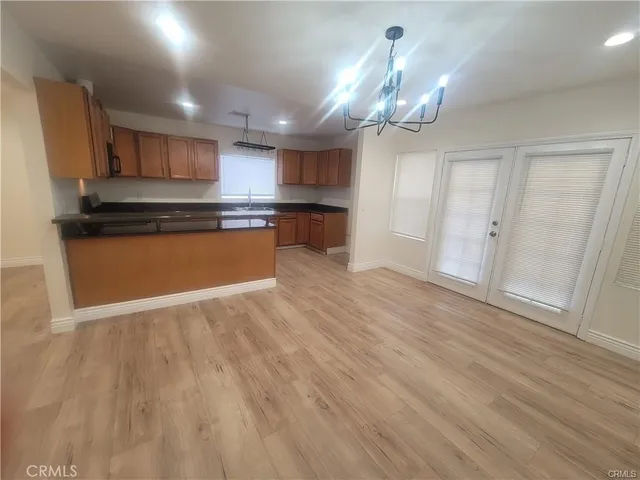 a kitchen with stainless steel appliances granite countertop a refrigerator a sink dishwasher a stove and a dining table with wooden floor