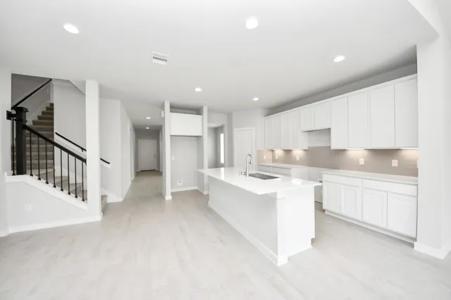 a view of a kitchen with a sink and dishwasher a stove top oven with wooden floor