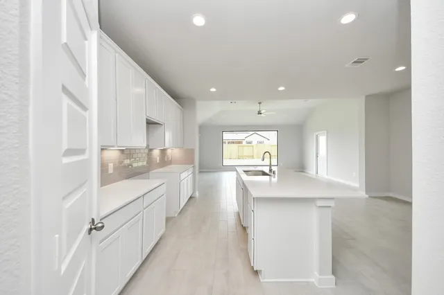 a kitchen with white cabinets appliances a sink and a counter top space