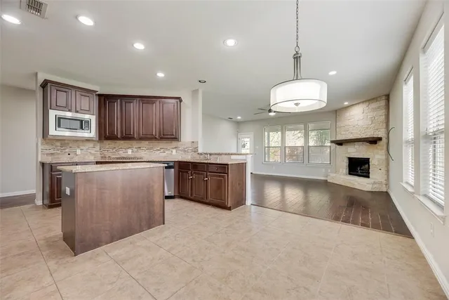 a kitchen with stainless steel appliances granite countertop a stove a sink a refrigerator and a microwave
