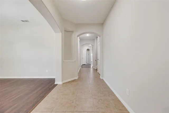 a view of a hallway with wooden floor and a bathroom