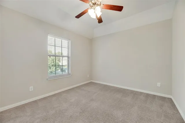 an empty room with chandelier fan and windows