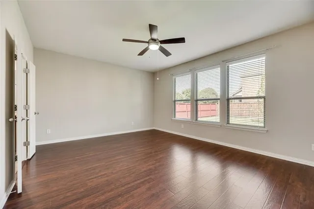 a view of empty room with wooden floor and fan