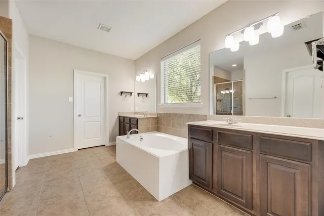 a spacious bathroom with a tub sink and mirror