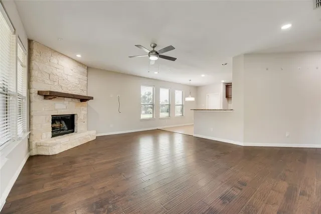 an empty room with wooden floor fireplace and windows