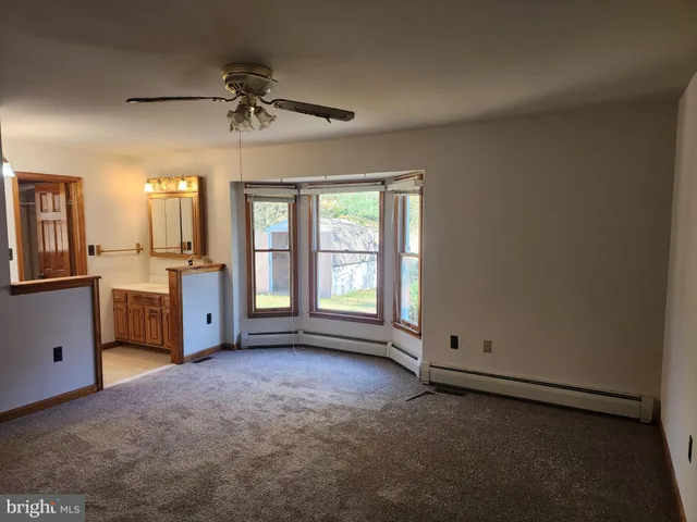 an empty room with chandelier fan and windows