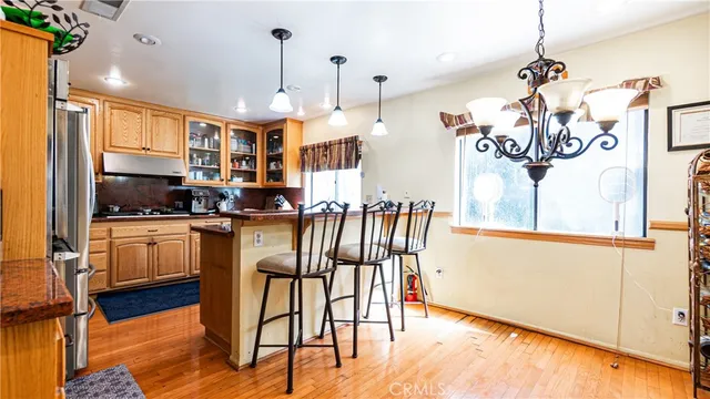 a kitchen with stainless steel appliances kitchen island granite countertop a stove a refrigerator a sink a dining table and chairs with wooden floor