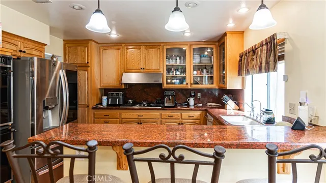 a kitchen with stainless steel appliances granite countertop a stove a refrigerator a oven a sink a dining table and chairs with wooden floor