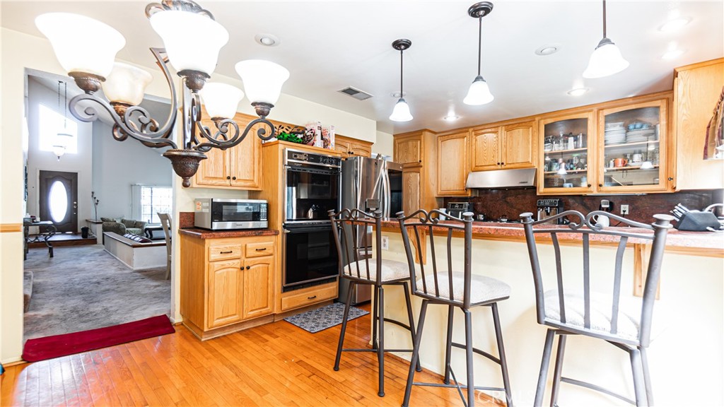 24220 Mentry Drive Newhall, CA 91321 - Photo 8 of 50 a kitchen with stainless steel appliances granite countertop a stove a refrigerator a oven a sink with island chairs and furniture