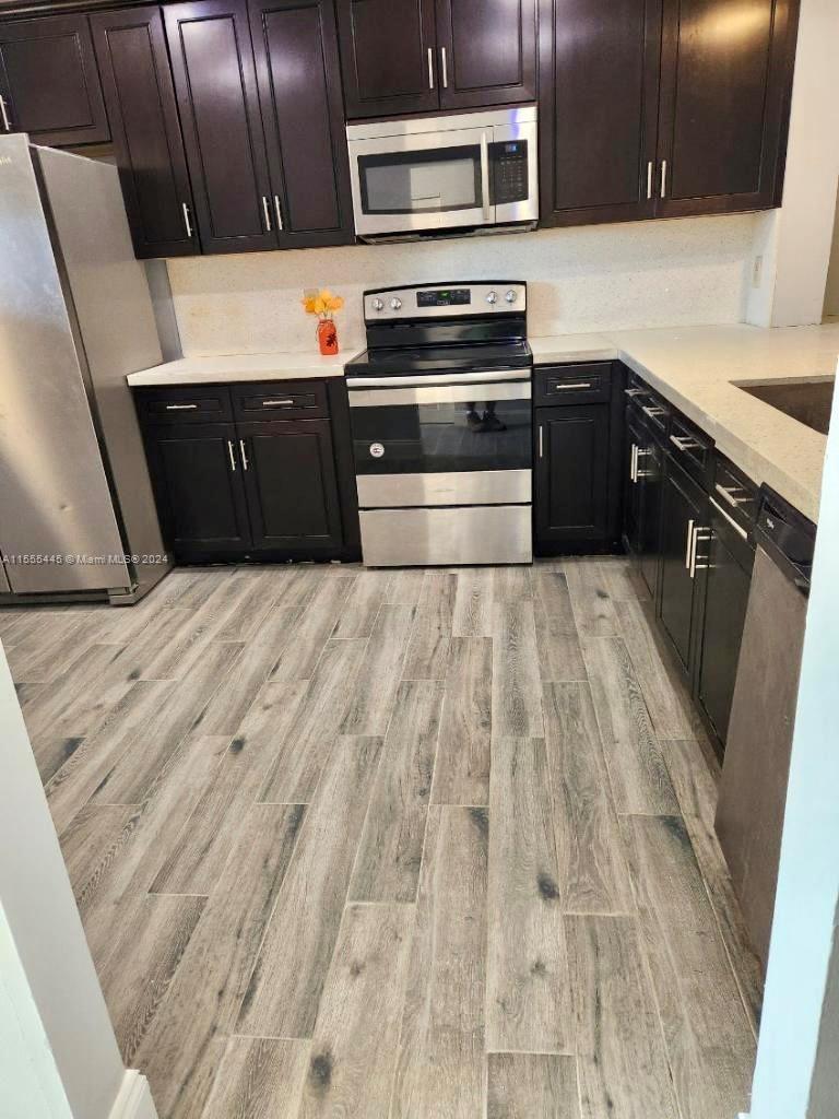 8765 Azalea Court, Unit 202 Tamarac, FL 33321 - Photo 3 of 9 a kitchen with wooden cabinets and stainless steel appliances