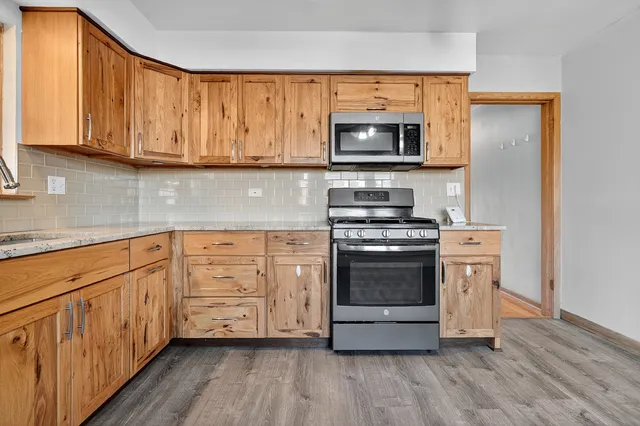 a kitchen with stainless steel appliances granite countertop a refrigerator a sink dishwasher and wooden cabinets