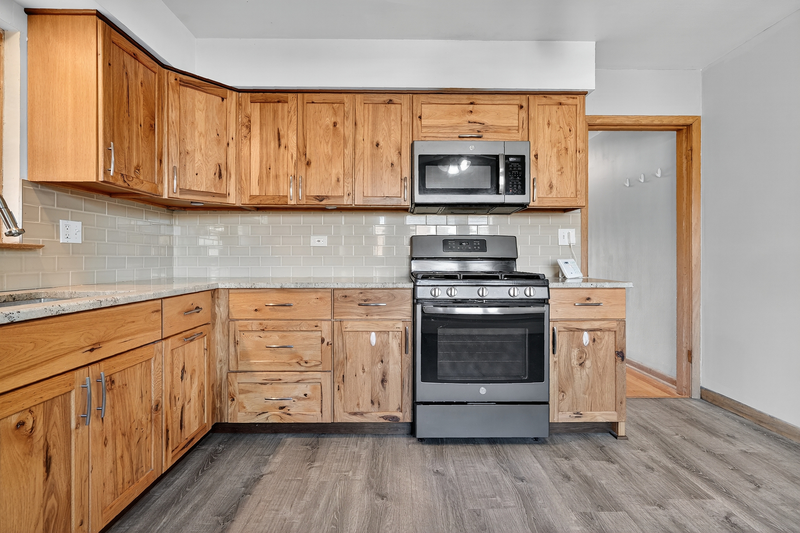 6408 West Raven Street, Unit 1 Chicago, IL 60631 - Photo 11 of 24 a kitchen with stainless steel appliances granite countertop a stove a sink and a microwave