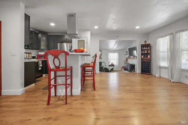 a dining hall with stainless steel appliances kitchen island granite countertop a dining table chairs and a refrigerator