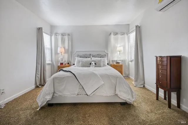 a bed sitting in a bedroom next to a window and a chair