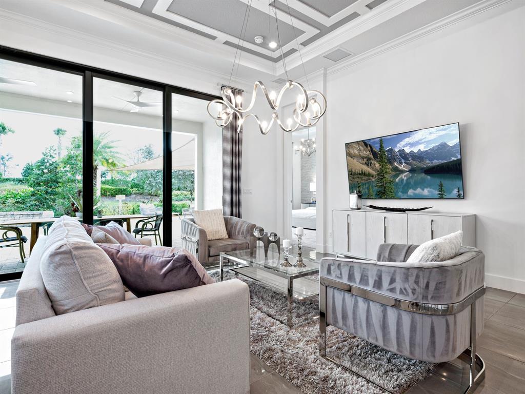 8146 Southwest Vanita Way Port St. Lucie, FL 34987 - Photo 11 of 53 a living room with furniture a flat screen tv and a floor to ceiling window