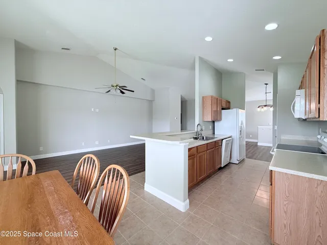 an empty room with a chandelier fan and windows