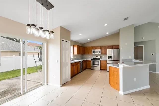 a kitchen with stainless steel appliances kitchen island granite countertop a refrigerator a oven and a sink