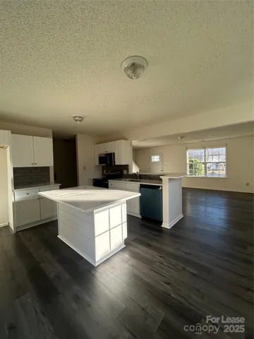 a kitchen with kitchen island granite countertop a sink cabinets and wooden floor