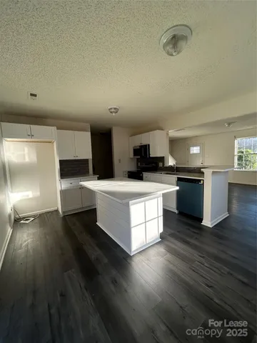 a kitchen with a sink wooden floor and black appliances