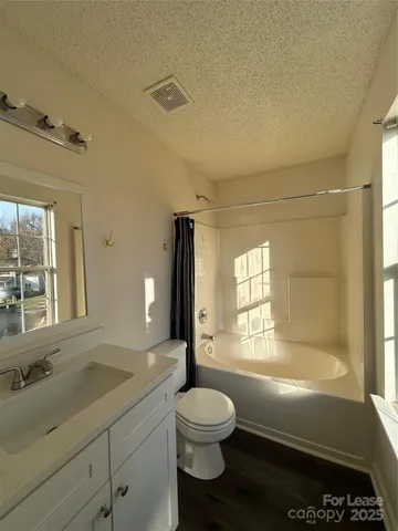 a bathroom with a granite countertop sink toilet a large mirror a bathtub and next to a window