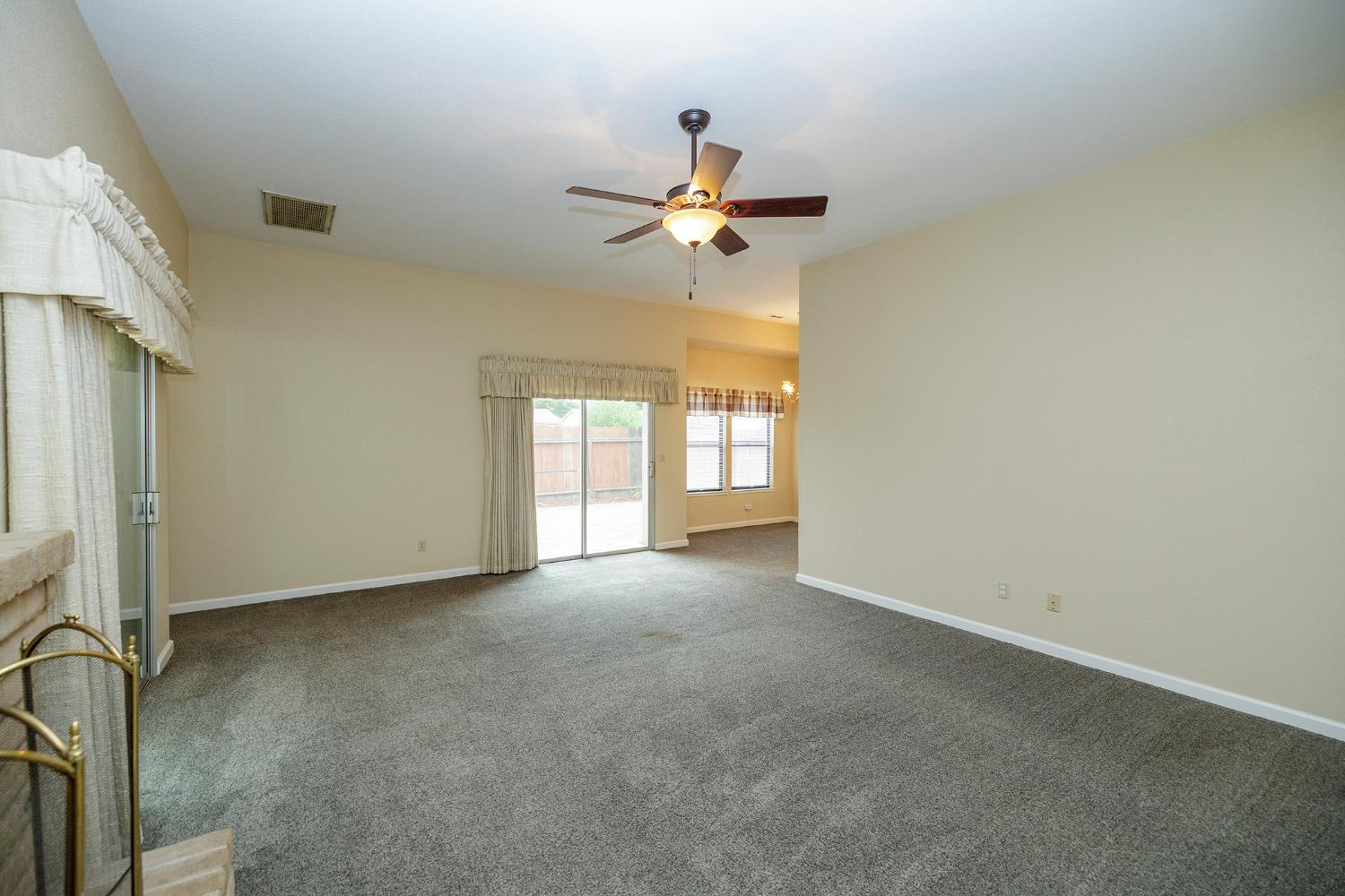 1124 Tasmania Way Modesto, CA 95356 - Photo 12 of 34 an empty room with windows and fan chandelier fan