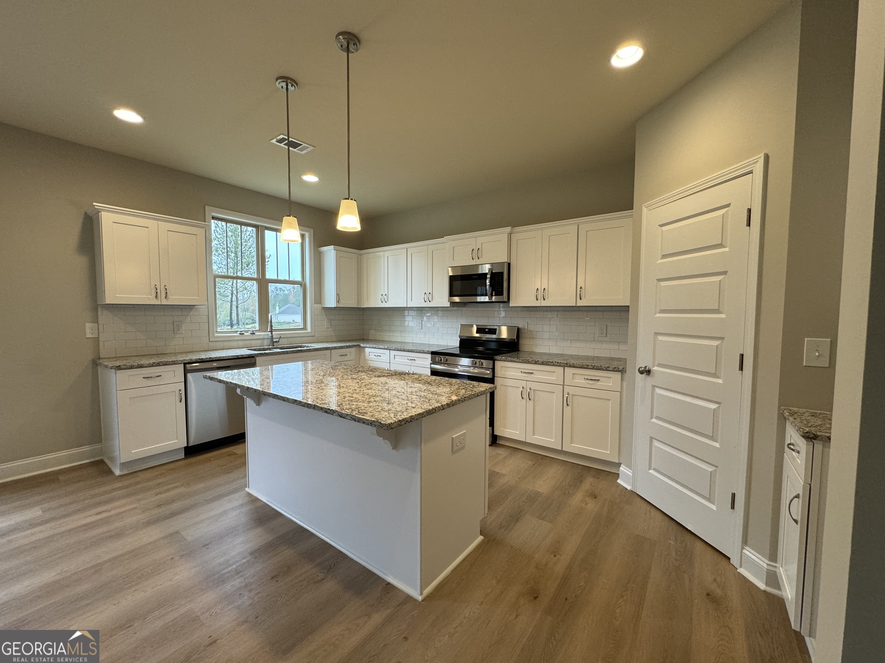 166 Country World Drive Macon, GA 31211 - Photo 2 of 33 a kitchen with kitchen island granite countertop a sink cabinets and wooden floor