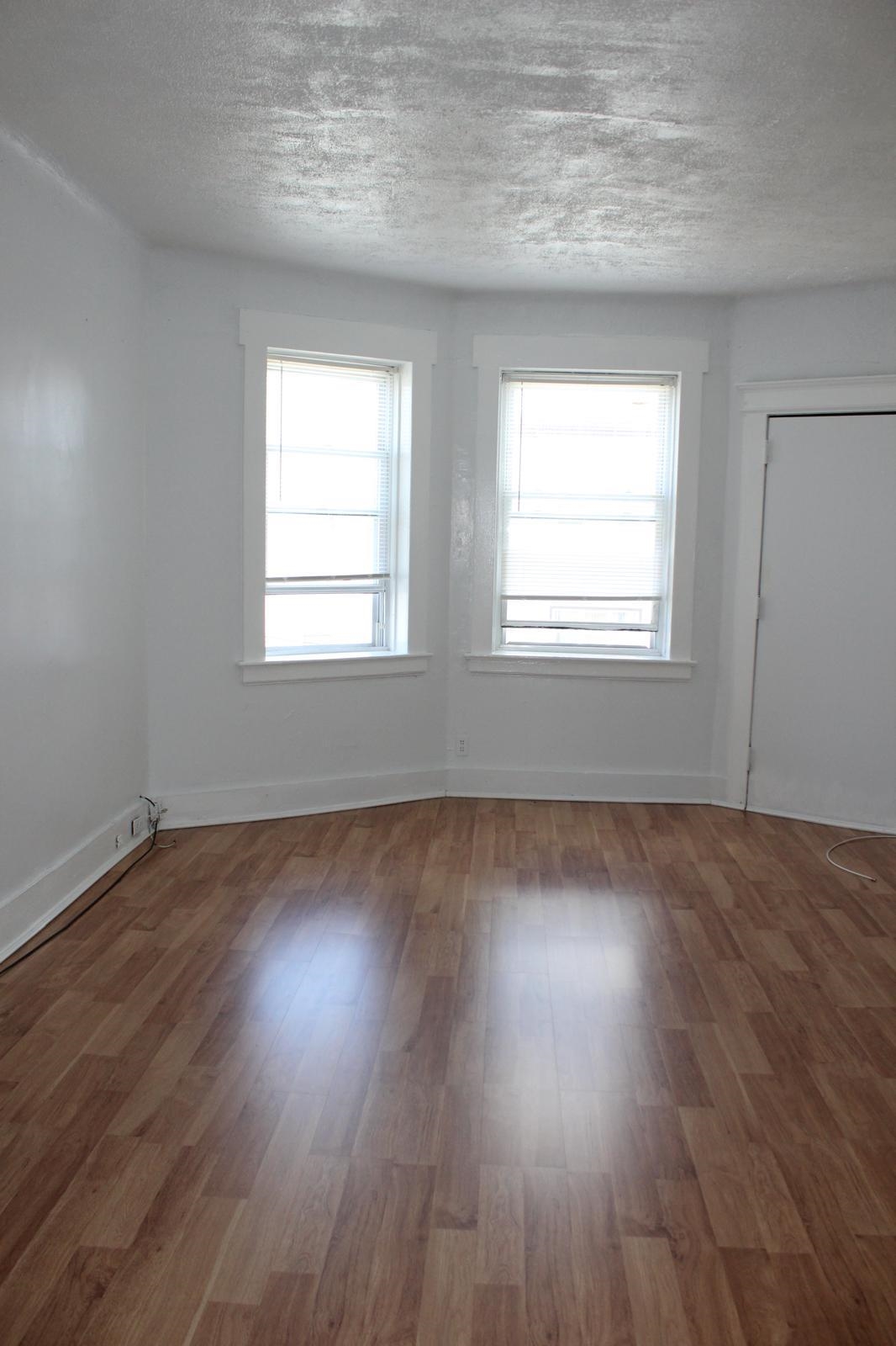 69 Poplar Street Jersey City, NJ 07307 - Photo 8 of 13 an empty room with wooden floor and windows