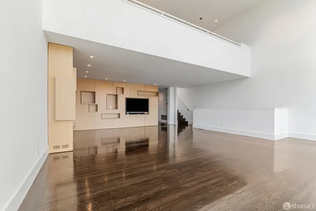 a living room with couches and kitchen view with wooden floor