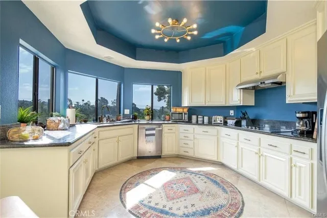 a white kitchen with a sink and chandelier