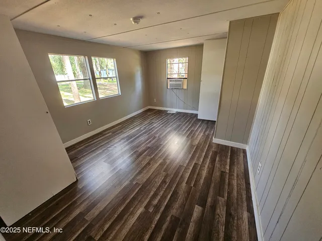 a view of hallway with window and wooden floor