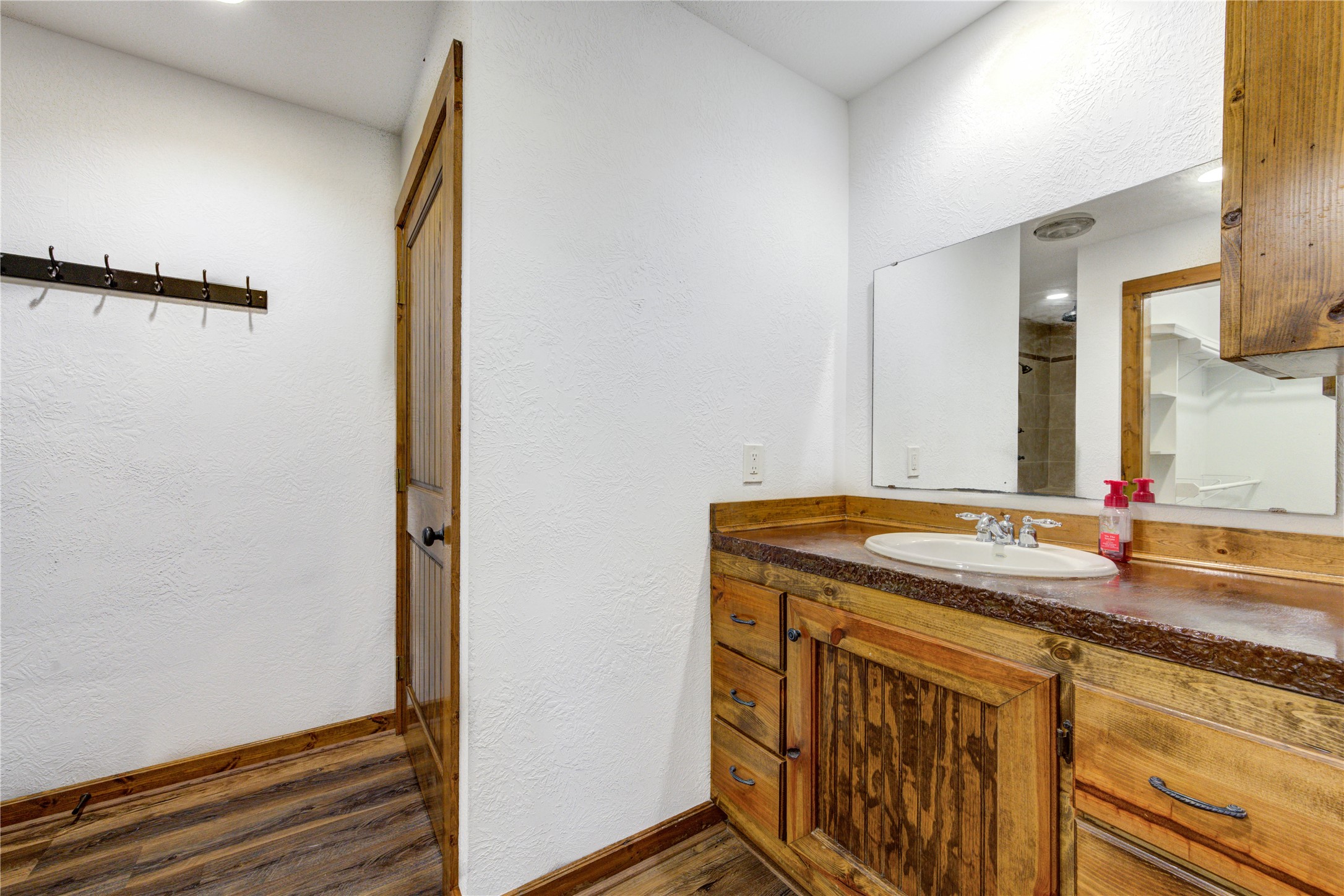 8805 Sun Oil Road Brenham, TX 77833 - Photo 35 of 50 Charming bathroom featuring rustic wood cabinetry, a spacious vanity with a large mirror, and warm wood accents, creating a cozy and inviting atmosphere.