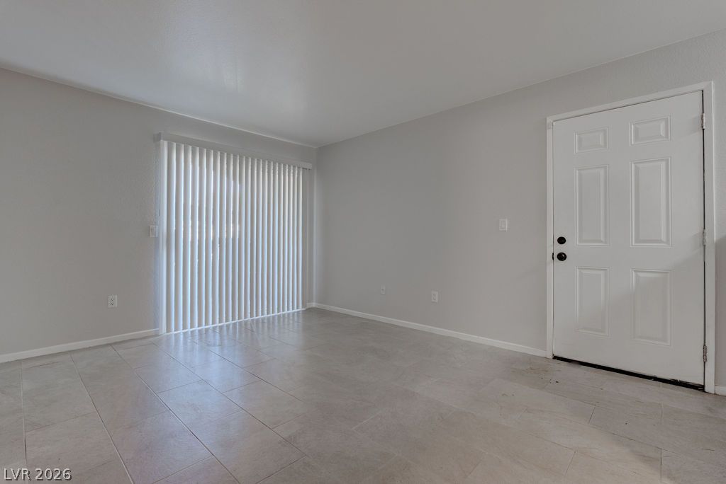 7885 West Flamingo Road, Unit 1016 Las Vegas, NV 89147 - Photo 3 of 24 A pristine, vacant room with light-toned walls and sleek tiled flooring, ready for personalization.